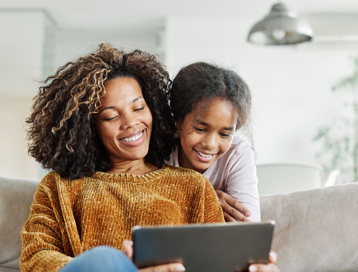 Mother and daughter looking at a tablet smiling